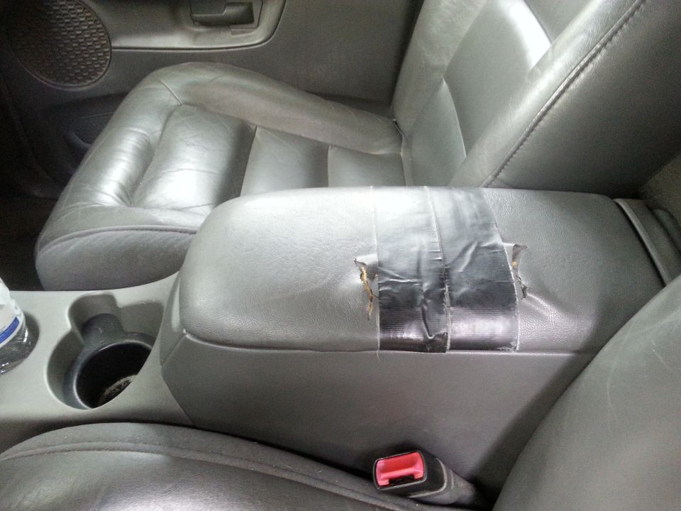 Gray interior center console armrest with duct tape repair