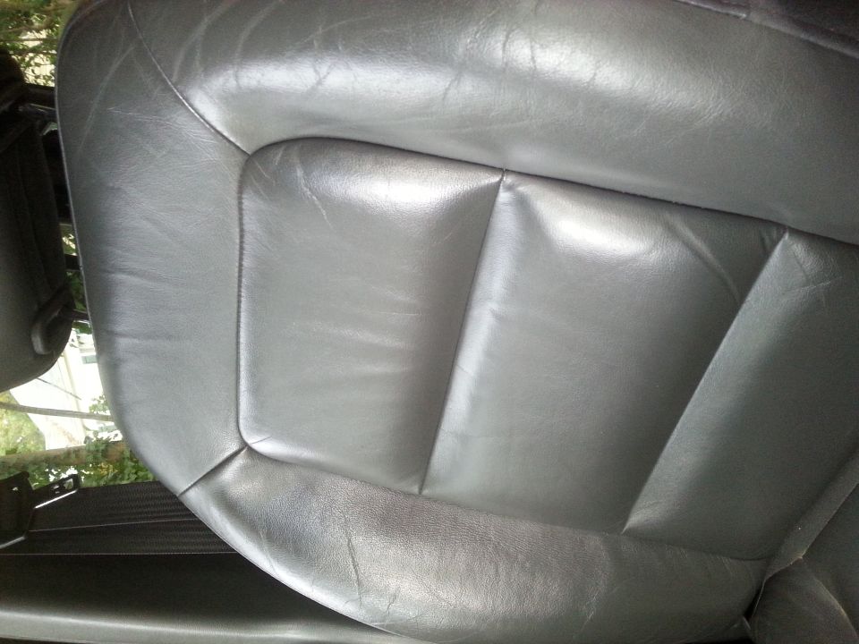 Gray leather car seat with visible stitching and some wear