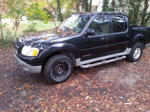2001 Ford Explorer - A black Ford Explorer Sport Trac is parked outdoors, covered in fallen autumn leaves.