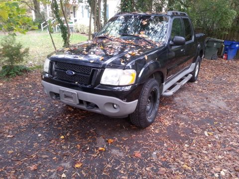 2001 Ford Explorer - A black 2001 Ford Explorer Sport Trac is parked outdoors, covered in fallen leaves.