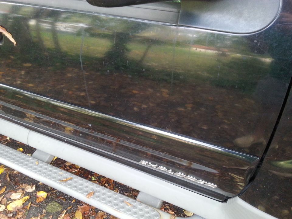 Dark SUV door trim with 'EXPLORER' badge and silver running board