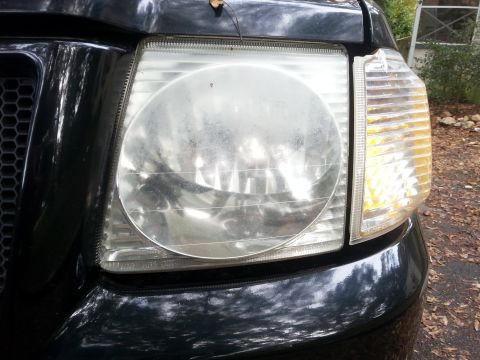 2001 Ford Explorer - A close-up view of the front of a black Ford Explorer, focusing on the headlight and grille assembly.