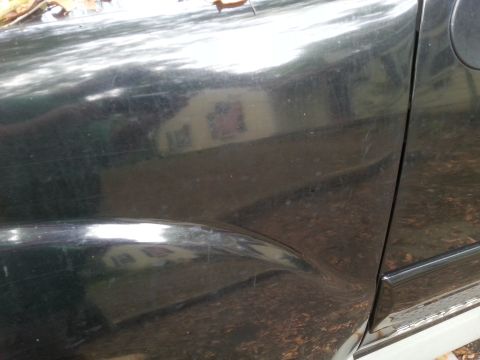 2001 Ford Explorer - A dented dark green SUV door and fender are visible, reflecting a house and trees in the background.