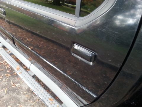 2001 Ford Explorer - Side view of a black SUV's door and running board, showing some wear and tear.
