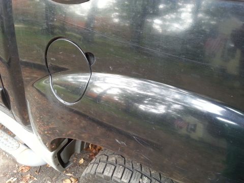 2001 Ford Explorer - This black SUV's rear quarter panel shows significant wear and tear, including scratches and a damaged fender flare.