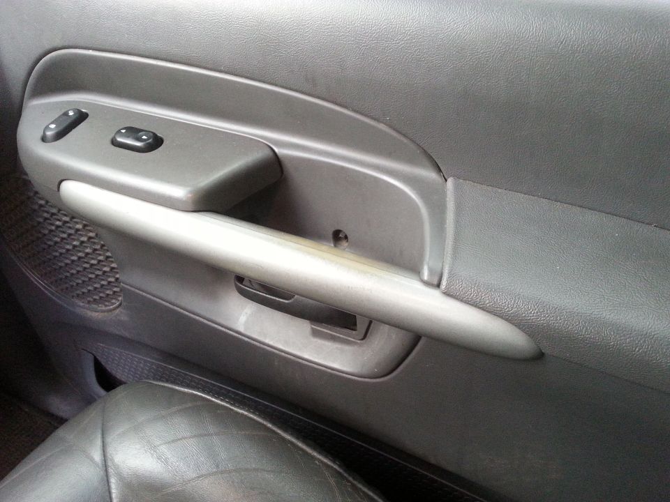 Interior door panel with power window controls and a silver pull handle. The seat is visible in the foreground