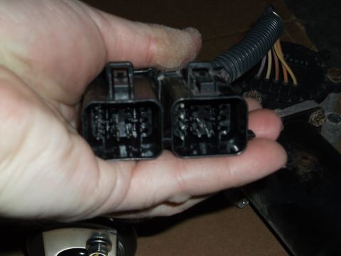 2005 Ford F-150 - hand holding two black multi-pin automotive electrical connector plugs over a vehicle interior work area.