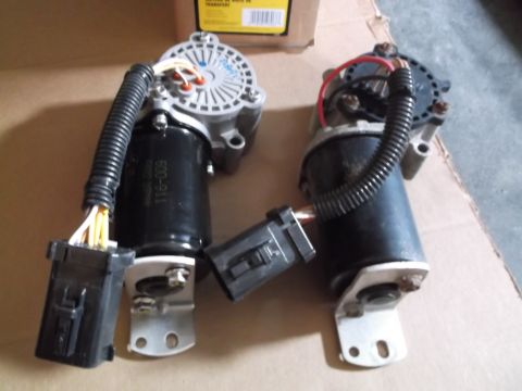 2005 Ford F-150 - Two transfer case shift motors are shown, one on the left and one on the right, resting on a cardboard surface. The motor on the left has a…