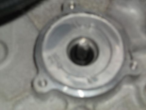 2005 Ford F-150 - A close-up, blurry view of a silver metal component with a hexagonal opening in the center, mounted to a textured gray surface. There are v…