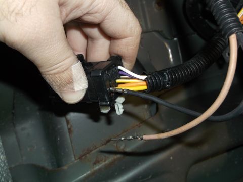 2005 Ford F-150 - A hand with a bandage on the thumb is holding a black electrical connector with multiple colored wires plugged into it. The connector is pa…