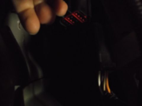 2005 Ford F-150 - Dim cabin photo of a hand reaching toward a red-and-black multi-pin electrical connector.