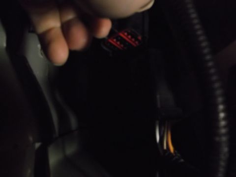 2005 Ford F-150 - A hand is shown reaching for a red and black electrical connector with multiple pins. The connector is part of a wiring harness visible in…
