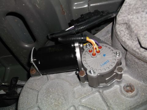 2005 Ford F-150 - A close-up view of a transfer case actuator motor and its wiring harness, mounted to a vehicle's drivetrain. The actuator has a gray housin…