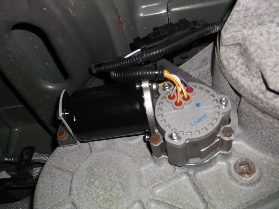 Transfer case actuator motor with wiring harness on a vehicle drivetrain