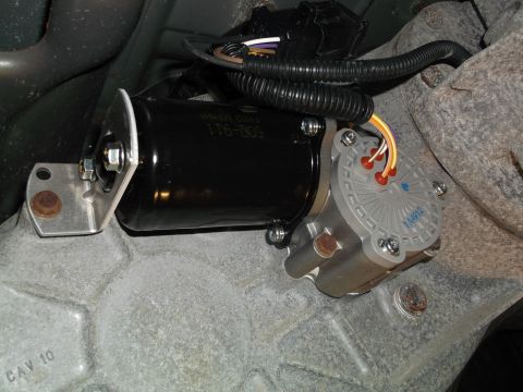 2005 Ford F-150 - A close-up view shows a black electronic actuator with a gray sensor housing attached to a gray metal vehicle component. The actuator has a…