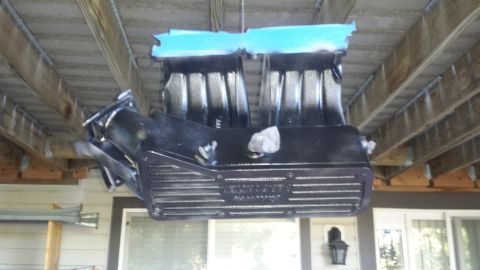 1996 Ford Bronco - A black automotive intake manifold is suspended and painted, with blue painter's tape covering the top surfaces. The part is hanging under…
