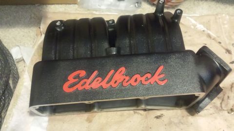1996 Ford Bronco - A black Edelbrock intake manifold with red lettering is shown in a close-up, angled view. The manifold is resting on a surface that appears…