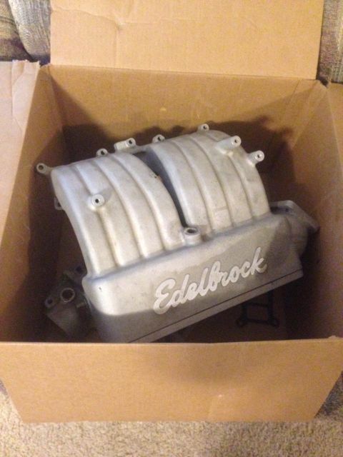 1996 Ford Bronco - A silver Edelbrock intake manifold is shown inside a cardboard box. The manifold has ribbed runners and the Edelbrock logo is visible on it…