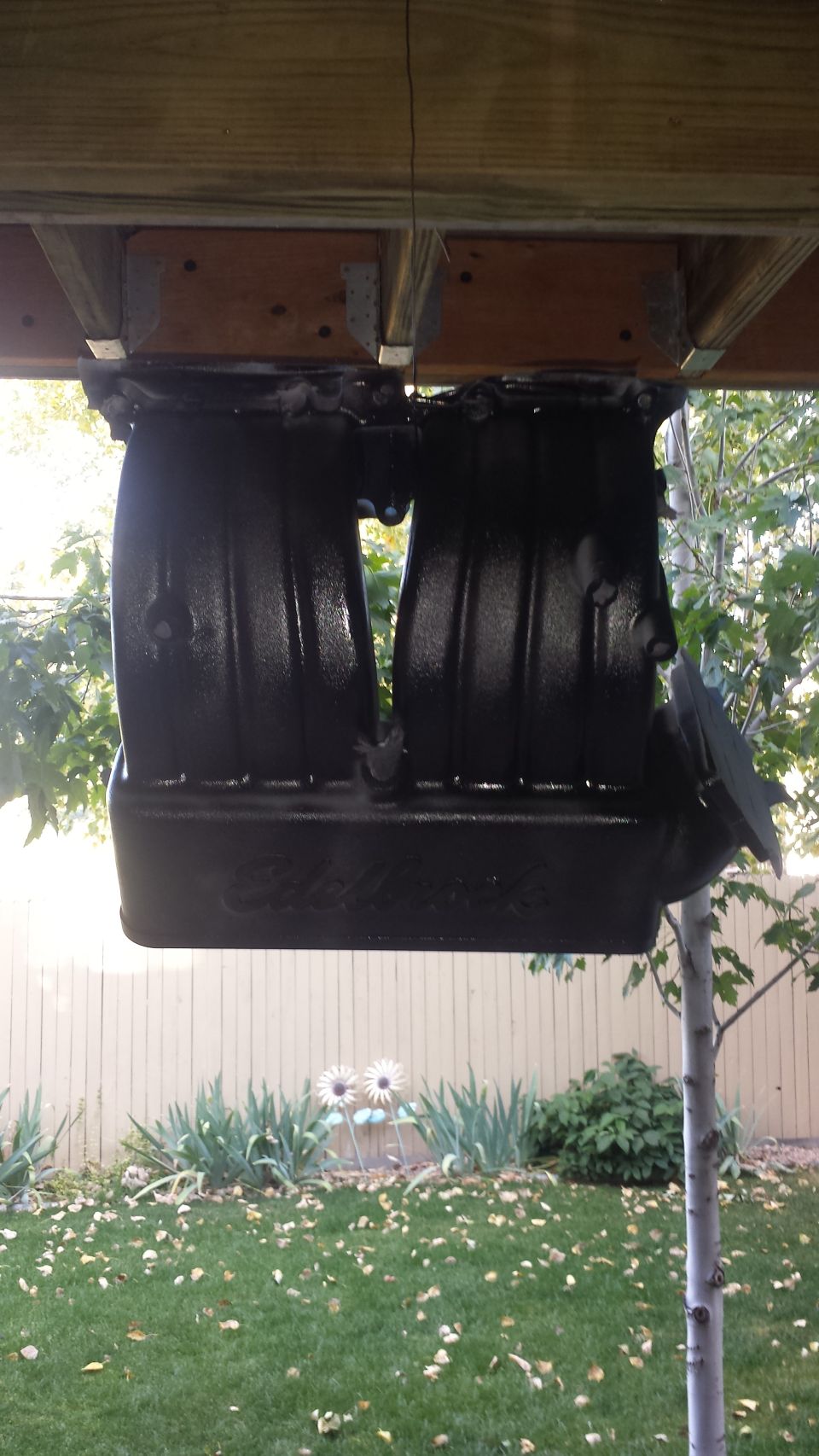 Black Edelbrock intake manifold mounted upside down under a deck.