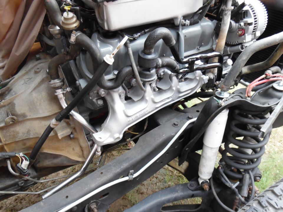 Silver-painted V8 engine in a black truck frame with white shock and coil spring visible