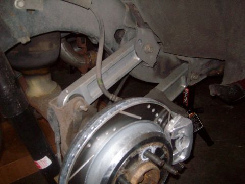 2004 Ford Crown Victoria - A close-up view of the rear suspension and braking system of a vehicle, likely a Ford Crown Victoria, showing the brake rotor, caliper, sho…