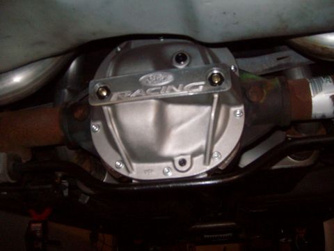 2004 Ford Crown Victoria - The underside of a Ford Crown Victoria shows a silver Ford Racing differential cover with visible bolts and exhaust pipes. The vehicle appe…