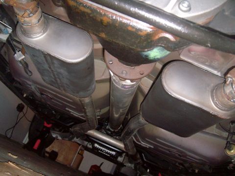 2004 Ford Crown Victoria - Underside view of a dual exhaust system on a Ford Crown Victoria, featuring two oval-shaped mufflers and a driveshaft. The exhaust pipes ar…