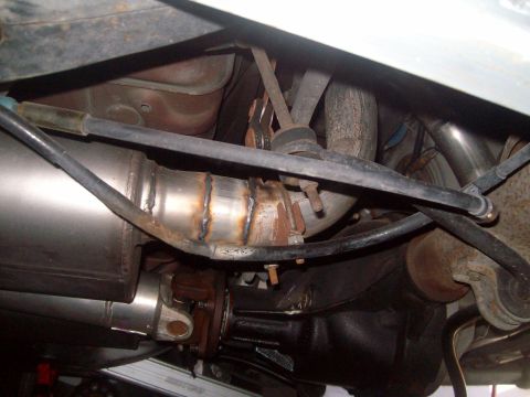 2004 Ford Crown Victoria - Underside view of a modified exhaust system on a vehicle, featuring a new muffler and piping with visible welds.
