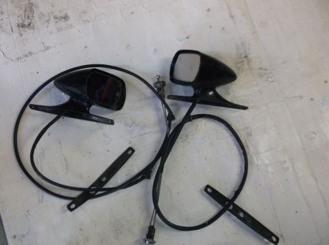 1979 Ford Ranchero - Two black side mirrors with cables are laid out on a white surface. Each mirror has a mounting bracket with screw holes.