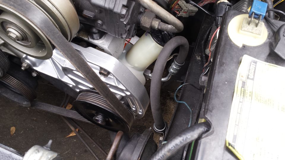 Engine bay close-up showing power steering pump, hoses, and pulleys.