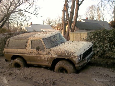1978 Ford Bronco - This vehicle is deeply stuck in thick mud, with its tires submerged.