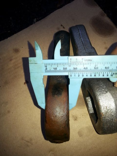 2001 Ford Explorer - A pair of metal objects, possibly tool heads, are being measured with a blue caliper. One object is dark and cylindrical with "VN32" visibl…