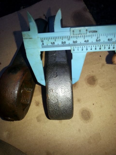 2001 Ford Explorer - A caliper is measuring the width of a metal part, likely a vehicle component, against a brown cardboard surface. The caliper's scale shows…