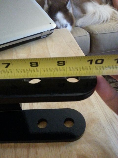 2001 Ford Explorer - A yellow measuring tape is placed over two black metal parts with holes. The tape shows measurements from 7 to 10 inches.