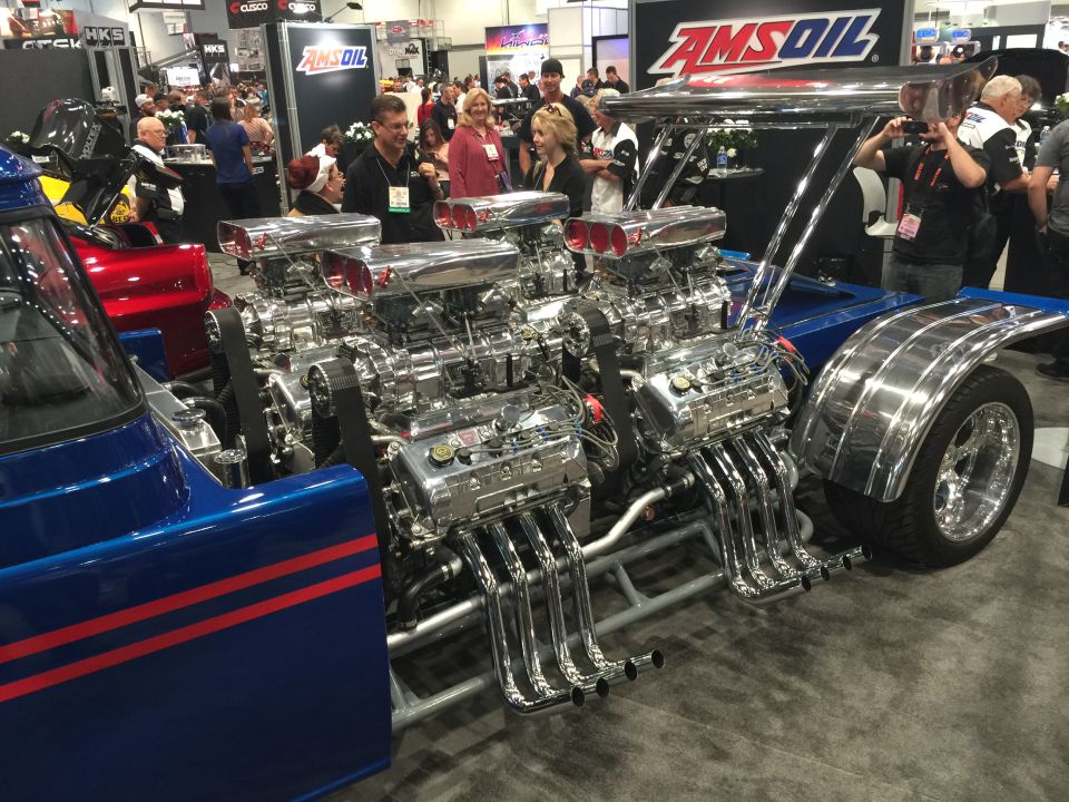 Blue hot rod with dual V8 engines and chrome exhaust pipes.