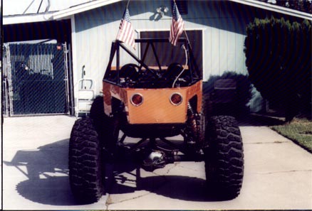 1990 Ford Bronco - This heavily modified vehicle features a roll cage and large off-road tires, with two American flags mounted on top.