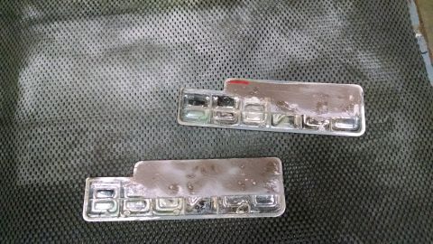 1992 Ford Bronco - Two chrome badges with individual letters are shown on a textured surface.