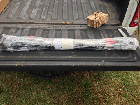 1979 Ford Bronco - Wrapped metal bars are placed on the tailgate of a truck, with a crumpled paper object nearby.