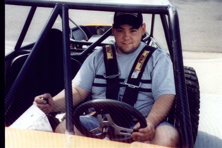 1990 Ford Bronco - Man in a racing buggy with a roll cage and safety harness.