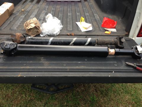 1979 Ford Bronco - Several driveshaft components are visible, along with some packaging and tools, resting on the tailgate of a pickup truck.