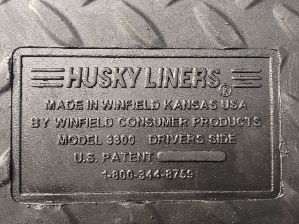 Close-up of a Husky Liners label on a floor mat, showing model 3300 and a phone number