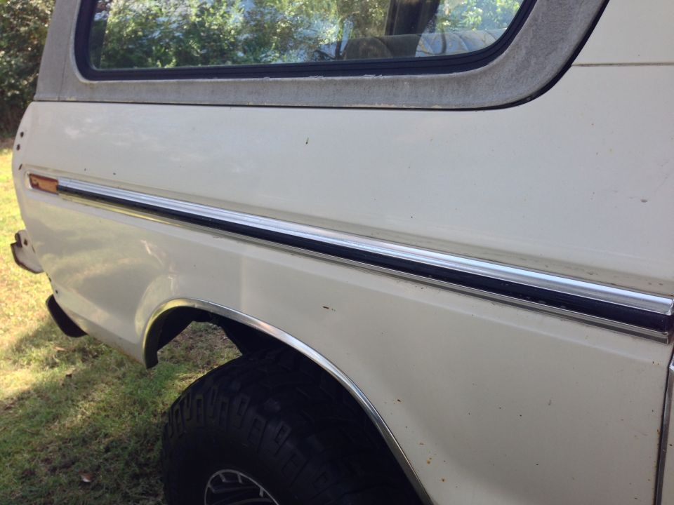 White SUV side view, showing a chrome trim strip and fender flare. The vehicle appears to be from the late 1970s