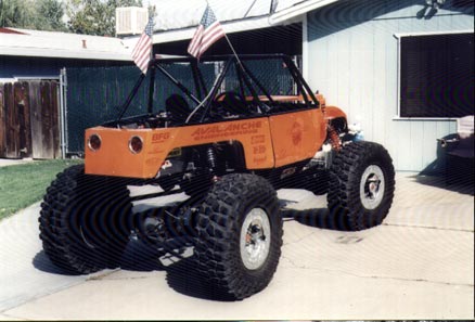 1990 Ford Bronco - This heavily modified off-road vehicle features a custom body, massive tires, and American flags.