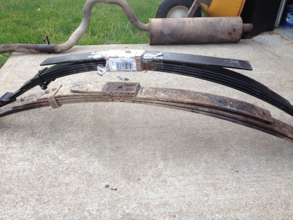 Two leaf springs and an exhaust pipe laid out on concrete