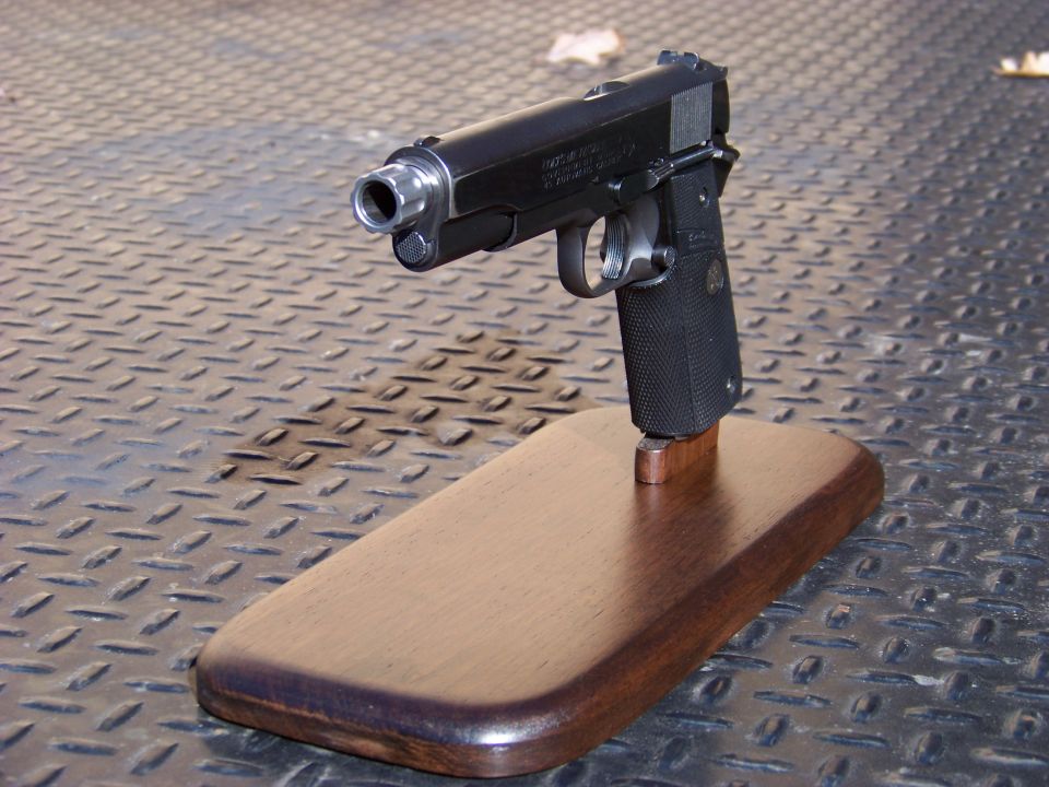 Black semi-automatic handgun on a wooden display stand.