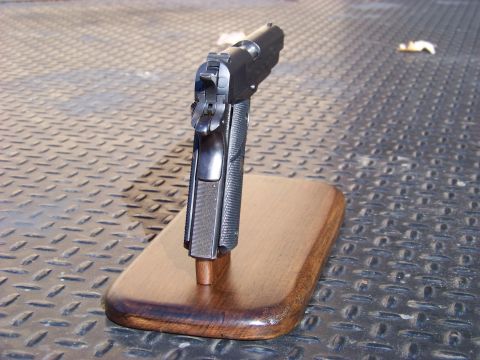 1995 Mercury Grand Marquis - A handgun is displayed on a wooden stand against a textured metal background.