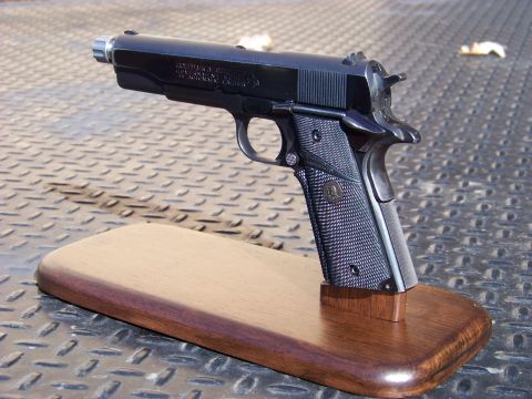 1995 Mercury Grand Marquis - A black semi-automatic handgun is displayed on a wooden stand. The handgun is a Colt Government Model 45 Automatic Caliber.