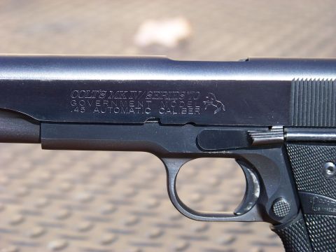 1995 Mercury Grand Marquis - A close-up, side view of a black Colt MK IV Series 70 Government Model .45 Automatic Caliber pistol. The pistol is resting on a textured su…