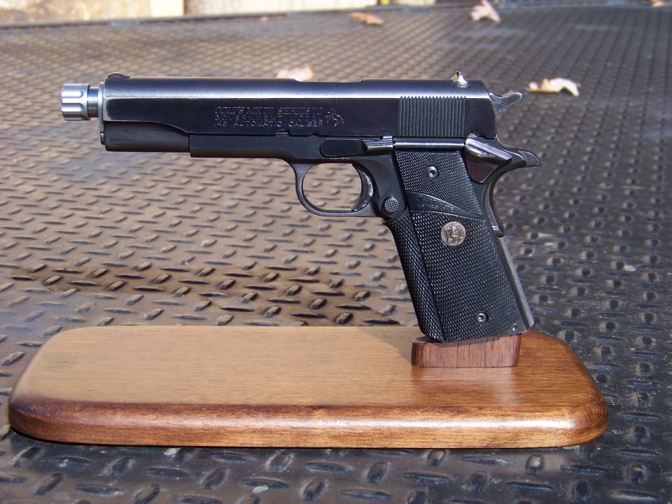 Black Colt M1911 pistol on a wooden display stand