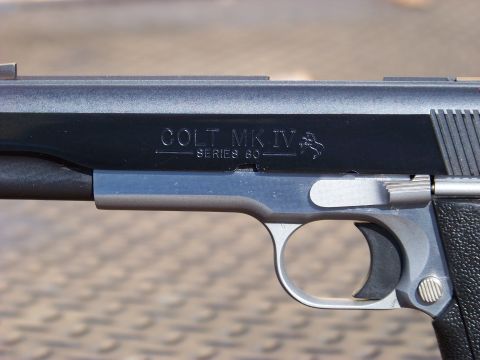 1995 Mercury Grand Marquis - A close-up, side view of a firearm with "COLT MK IV SERIES 80" engraved on the slide. The firearm has a black finish and a silver trigger a…